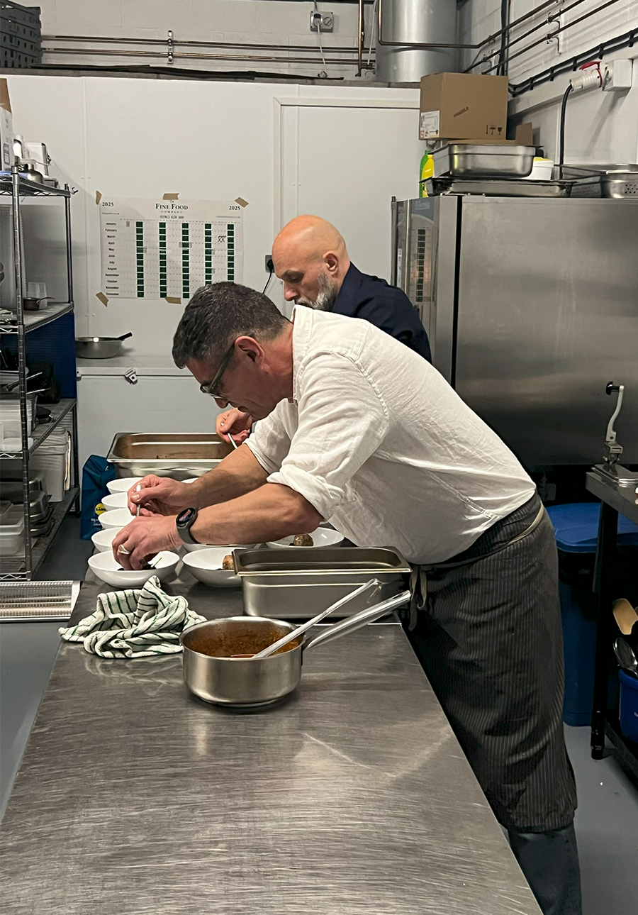 Two chefs preparing food in a professional kitchen.