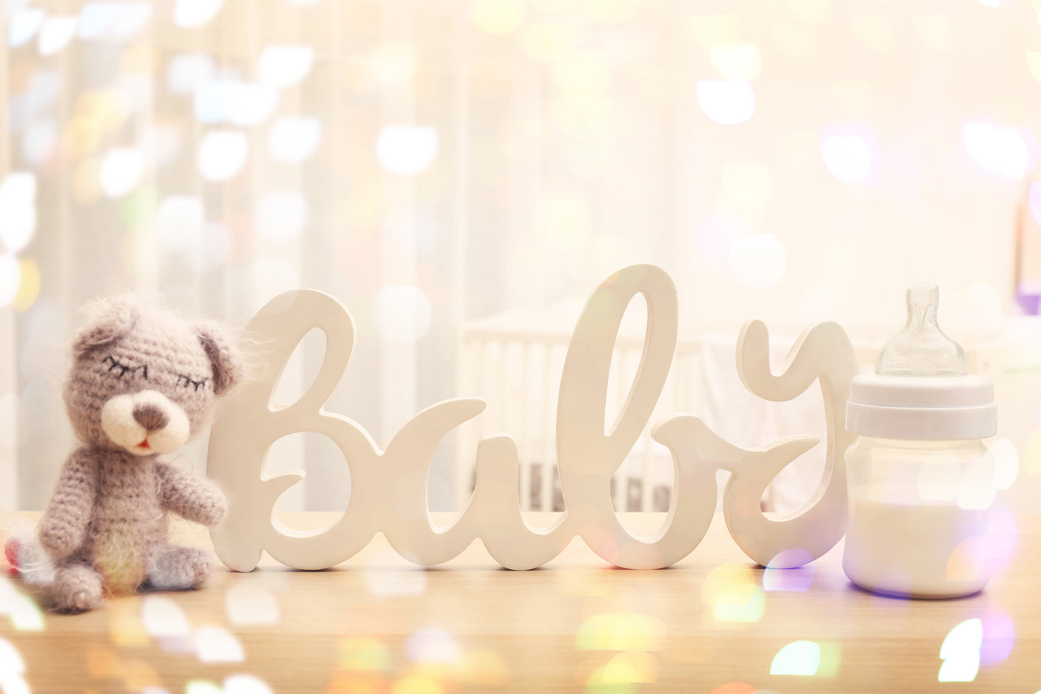 Decorative word 'Baby' with a teddy bear and bottle on a blurred background