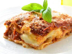 Slice of lasagna with basil on a white plate