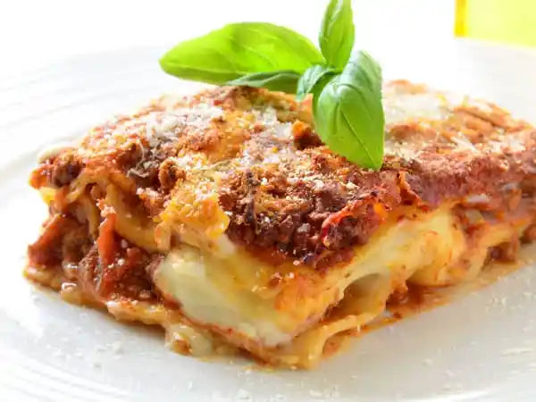 Slice of lasagna with basil on a white plate