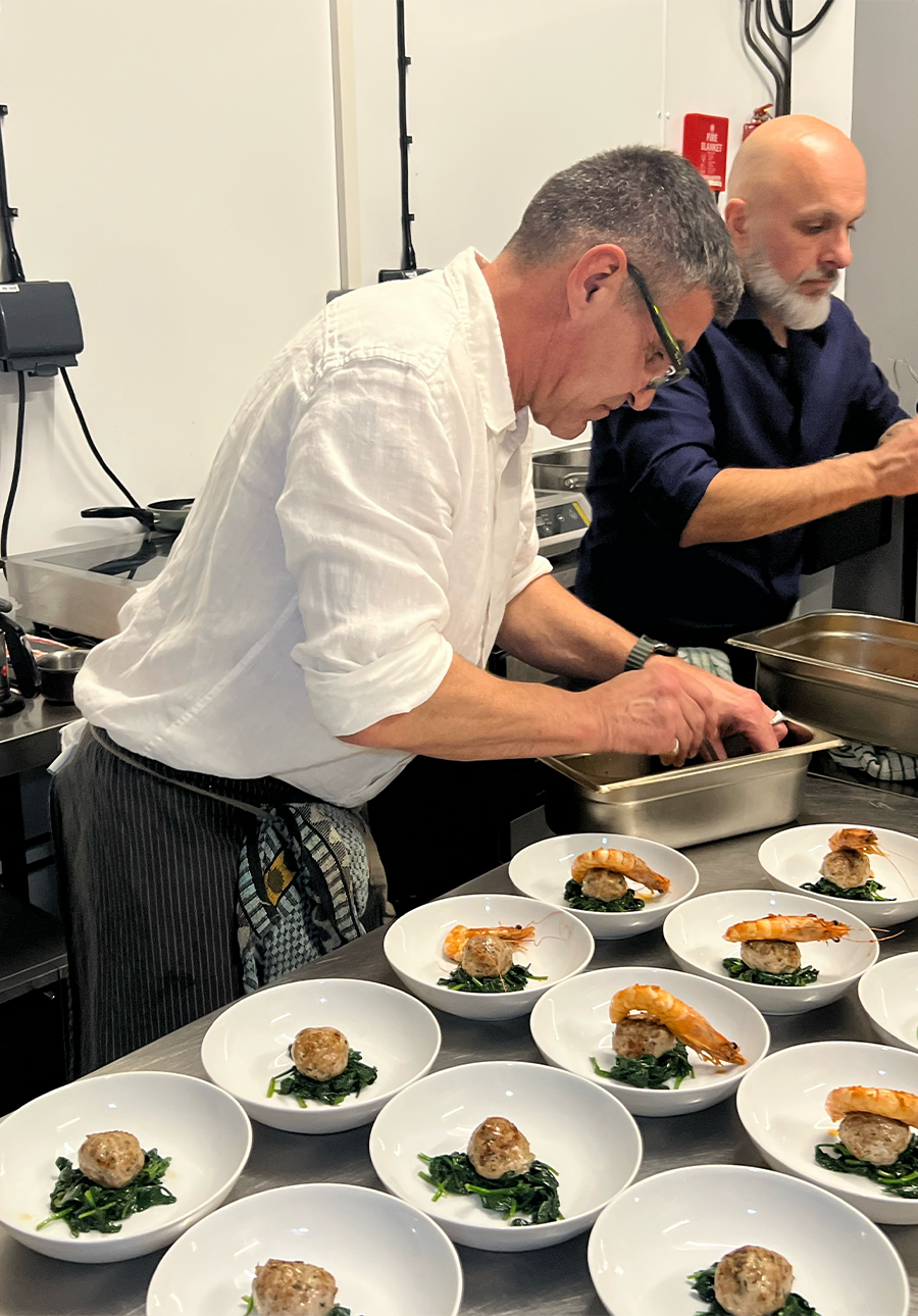 Chef Christophe preparing dishes in a kitchen with multiple bowls of food.